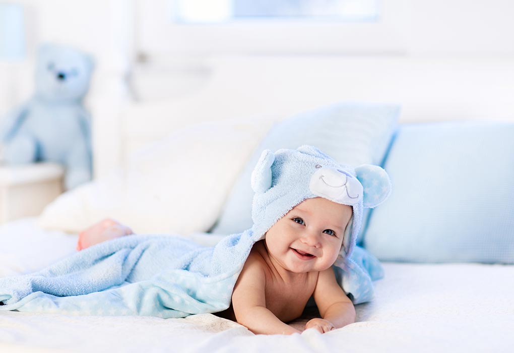 bebelus fericit invelit cu paturica albastra