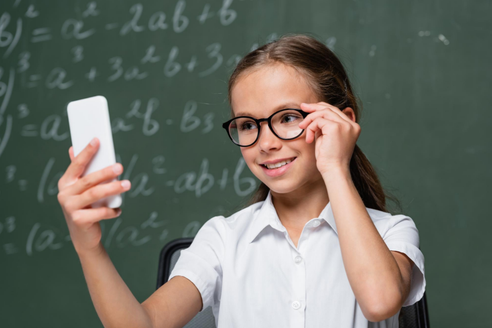 fetita in clasa cu ochelari de vedere care sta pe telefon in timpul orelor si este distrasa