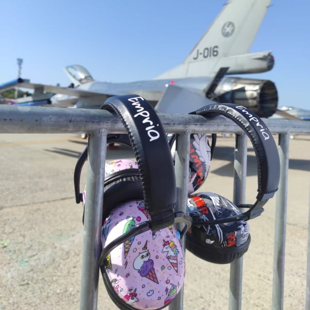 imagine cu doua casti antifonice brand Empria agatate pe gardul de la Romaero Baneasa iar in fundal este un avion supersonic