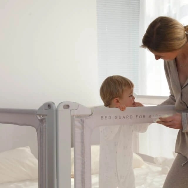 imagine cu bebe in pat si mama langa patul are o bariera de protectie pentru copii