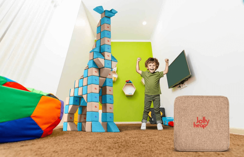 copil bucuros care sta langa o constructie din cuburi magnetice JollyHeap in forma de girafa