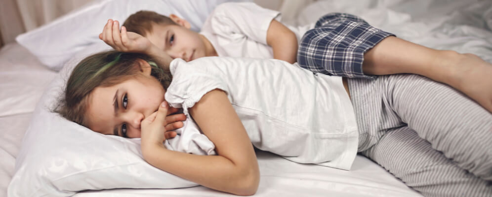 doi copi care se pregatesc de culcare, stau intinsi in pat