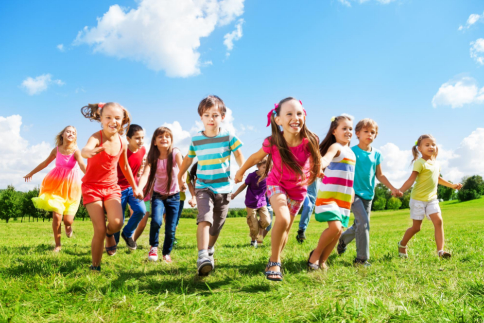 multime de copii in iarba care alearga si sunt fericiti intr-o zi senina