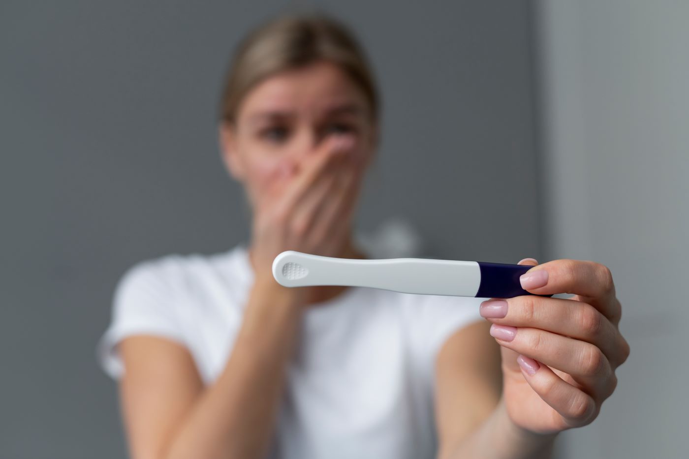 femeie uimita care citeste un test de sarcina