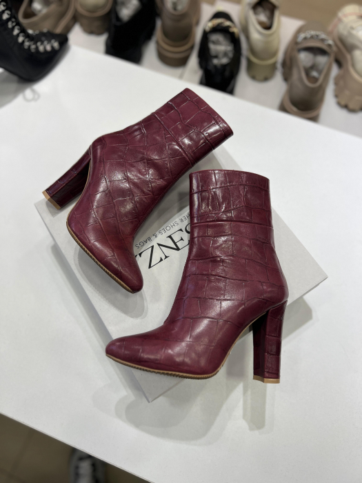 Botine din piele rosie cu textura croco.Botinele au un  toc gros de 9.5 cm ce confera stabilitate. [3]