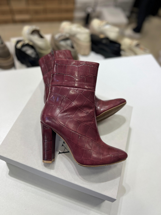Botine din piele rosie cu textura croco.Botinele au un  toc gros de 9.5 cm ce confera stabilitate. [4]