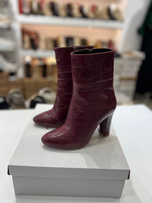 Botine din piele rosie cu textura croco.Botinele au un  toc gros de 9.5 cm ce confera stabilitate. [1]