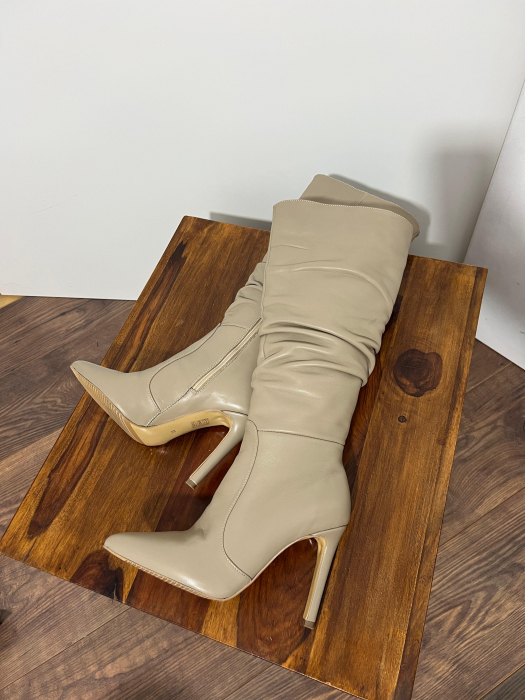 Cizme cu varf ascutit, cu pliuri, din piele naturala bej. Barntul este acoperit integral cu burete, adaugand un plus de confort. Inchiderea se face cu fermoar interior [4]