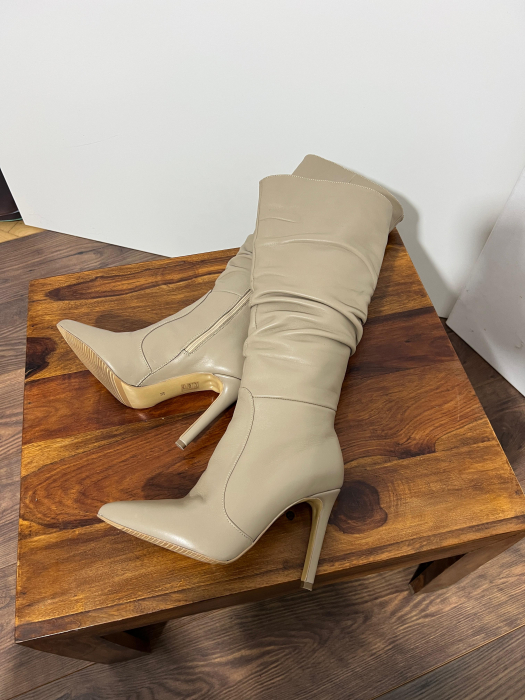 Cizme cu varf ascutit, cu pliuri, din piele naturala bej. Barntul este acoperit integral cu burete, adaugand un plus de confort. Inchiderea se face cu fermoar interior [1]