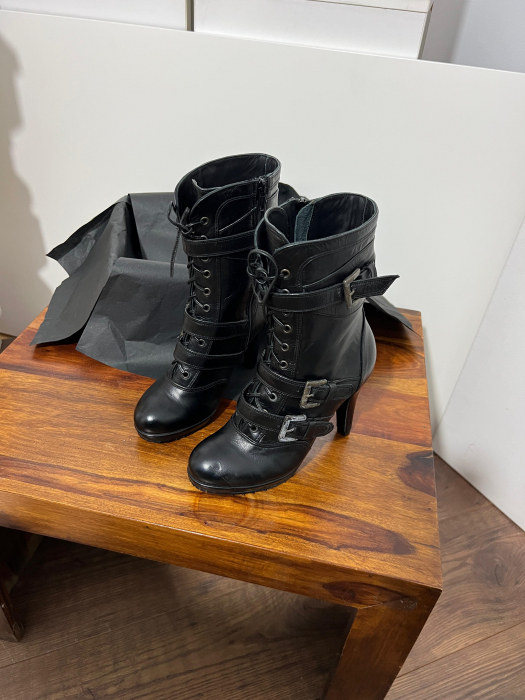 Ghete din piele naturala neagra, catarame de decor si talpa antiderapanta. Aceste ghete au un fermoar interior pentru incaltare rapida si usoara. [3]