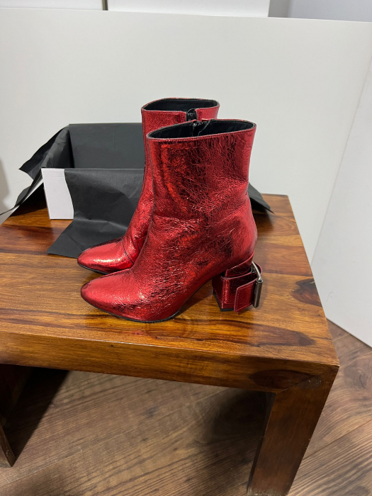 Ghete din piele rosie, cu toc gros de 8.5 cm, ce confera stabilitate. [1]