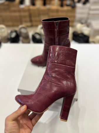 Botine din piele rosie cu textura croco.Botinele au un  toc gros de 9.5 cm ce confera stabilitate. [1]