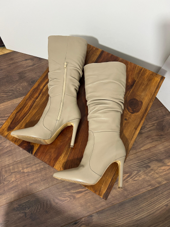 Cizme cu varf ascutit, cu pliuri, din piele naturala bej. Barntul este acoperit integral cu burete, adaugand un plus de confort. Inchiderea se face cu fermoar interior [1]