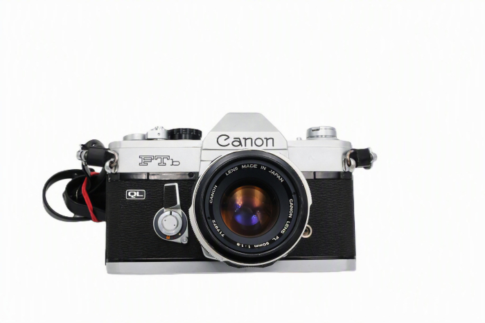 Kit aparat foto SLR pe film 35mm Canon FTb QL second hand în finisaj argintiu, cu obiectivul Canon Lens FL 50mm F1.8 montat și capacul frontal așezat alături pe fundal alb izolat. [2]