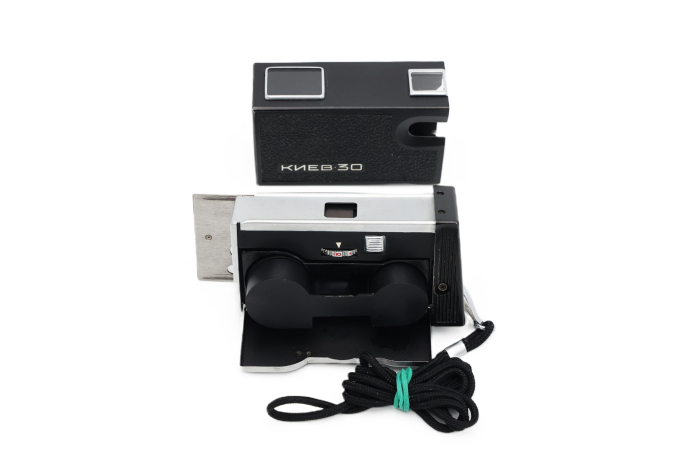 Aparat foto subminiatură de spionaj Kiev 30 second hand, variantă pe negru, în poziție deschisă (culisat) cu marcajele de expunere superioare și șnurul de mână textil inclus. [5]