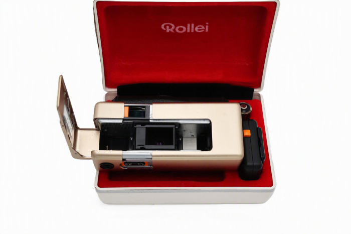Aparat foto subminiatură de lux Rollei A110 Ediția Gold Atom second hand, așezat în caseta sa originală căptușită cu catifea roșie, alături de husa de piele și adaptorul de blitz. [5]