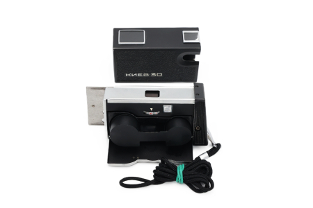 Aparat foto subminiatură de spionaj Kiev 30 second hand, variantă pe negru, în poziție deschisă (culisat) cu marcajele de expunere superioare și șnurul de mână textil inclus. [4]