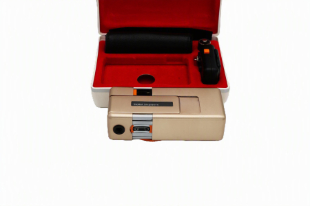 Aparat foto subminiatură de lux Rollei A110 Ediția Gold Atom second hand, așezat în caseta sa originală căptușită cu catifea roșie, alături de husa de piele și adaptorul de blitz. [3]