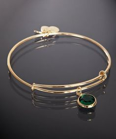 O brățară simplă cu piatră prețioasă verde, pe un fundal negru elegant. [1]