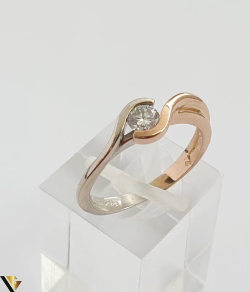 Inel din aur 18k, 750 3.63 grame Diamant de cca 0.27ct Contrast realizat prin folosirea aurului al si roz Latime maxima  de 6 mm Diametrul inelului este de 17mm (masura standard RO: 54si UE: 16) Marcaj cu titlul "750" Locatie HARLAU [1]