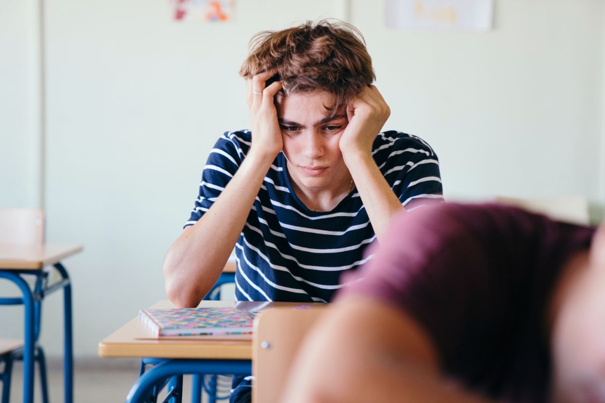 1. canabis in ADHD - adolescent preocupat, tricou albastru in dungi, caiet, sala de clasa