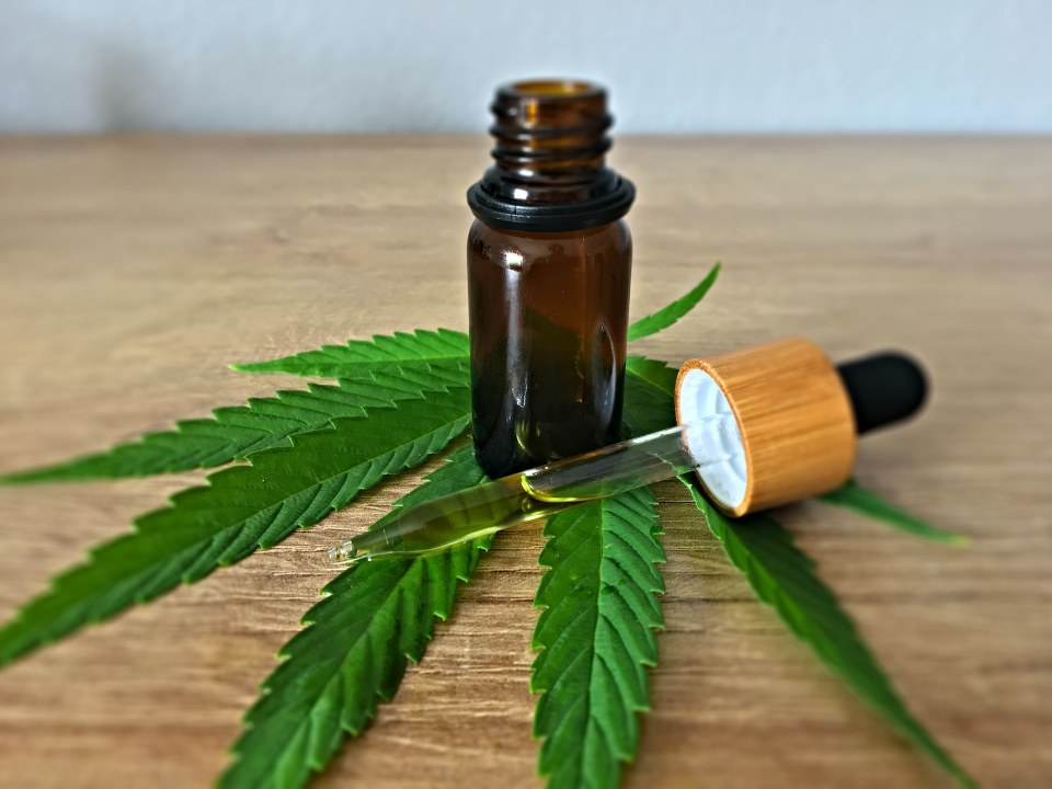 2.3. CBD pentru durerea provocata de inflamatii - o sticluta cu o pipeta langa ea, peste o frunza de cannabis sativa