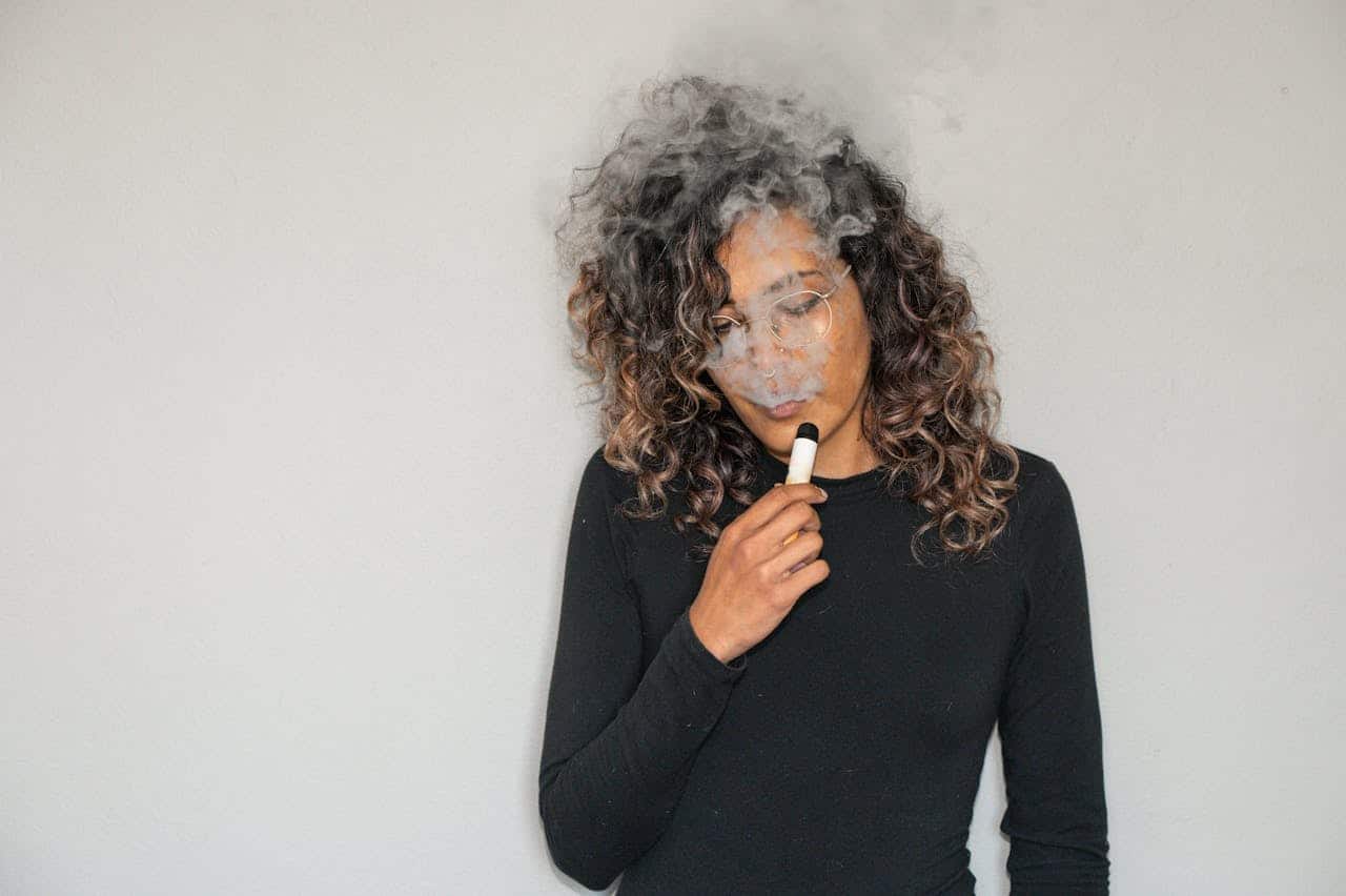 2. CBD cristale - femeie, vape, bluza neagra, ochelari de vedere, fundal gri