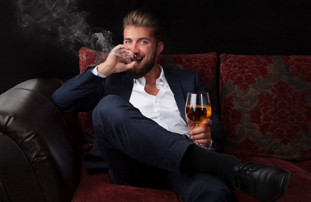 3. Cadouri pentru barbatii fumatori cu gusturi fine- barbat in costum, cu trabuc si pahar de vin-min