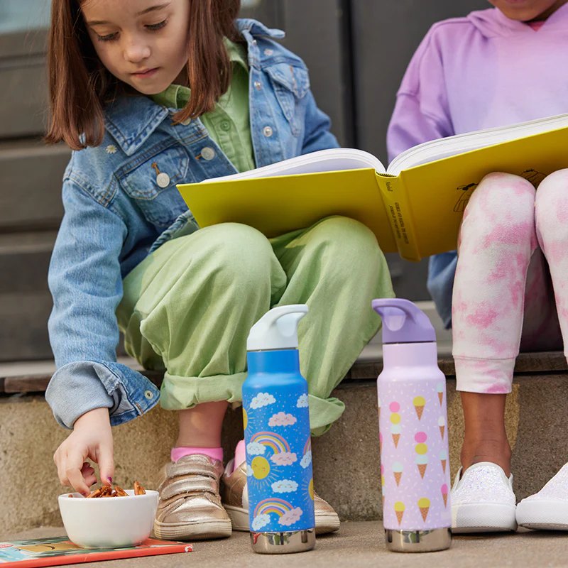 Două termosuri Kid Kanteen® colorate, lângă doi copii care citesc pe scări