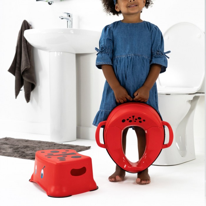 Fetiță cu reductorul roșu My Carry Potty, lângă treapta asortată