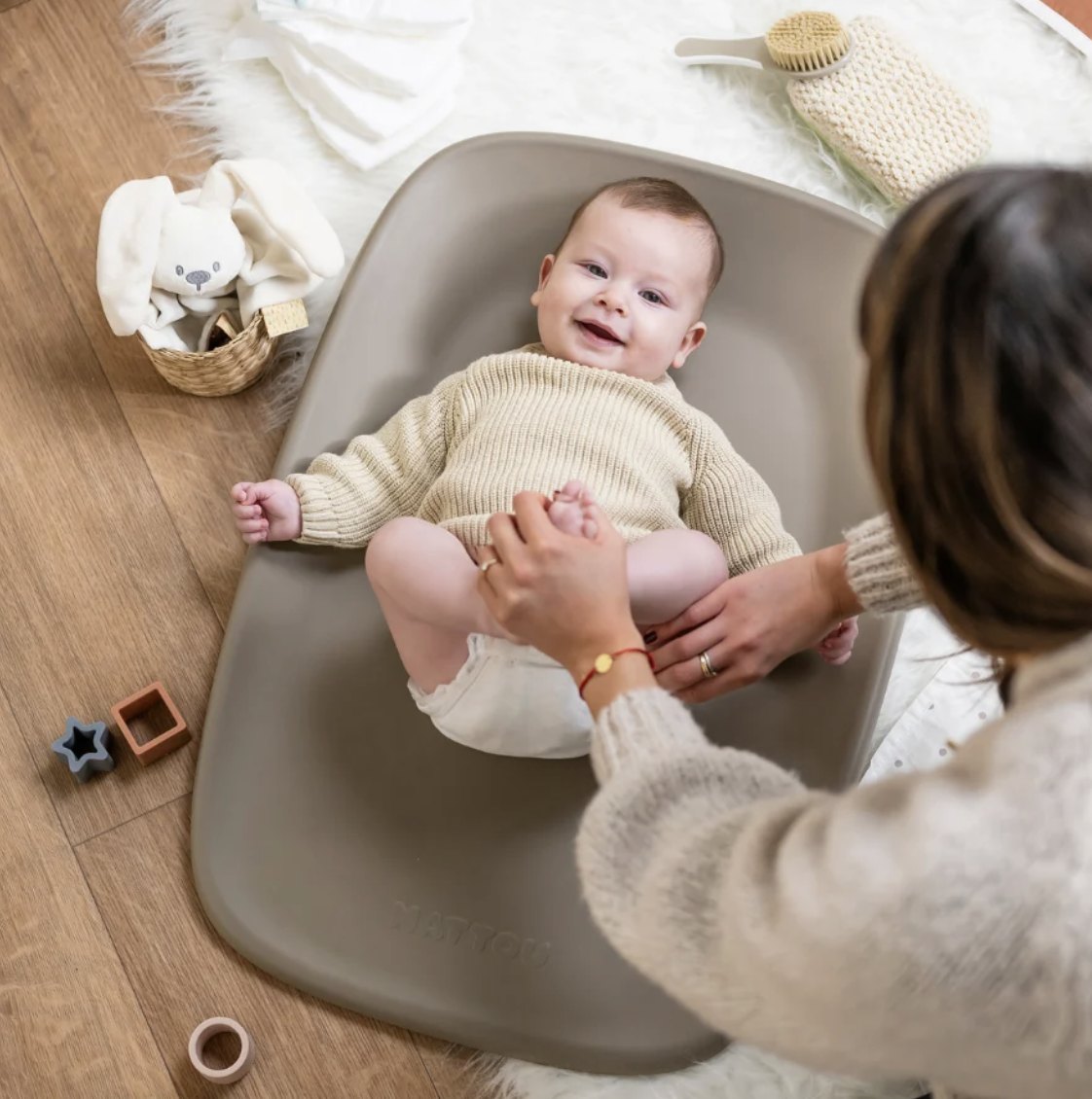Mamă care schimbă bebelușul pe o saltea de schimbat Nattou