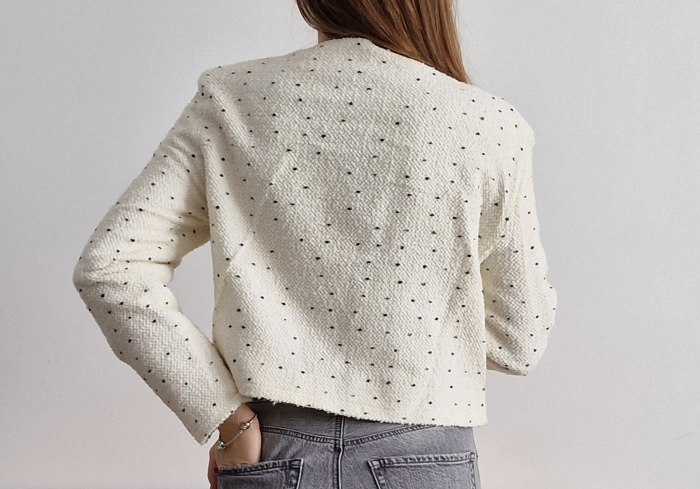 Sacou alb de damă, fără guler, buzunare sau închidere. Cu imprimeu fin de buline albe, mânecă lungă și croi până la talie. Ideal pentru outfituri de zi sau birou. [3]