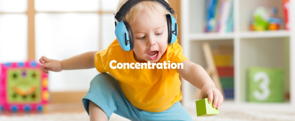 copil mic care se joaca cu cuburile acasa si are casti antifonice pe cap