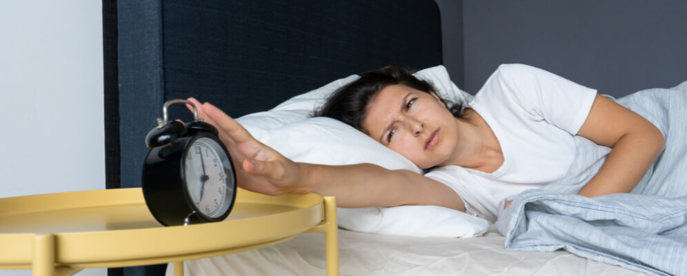 femeie care tocmai s-a trezit pentru ca suna alarma si este morocanoasa