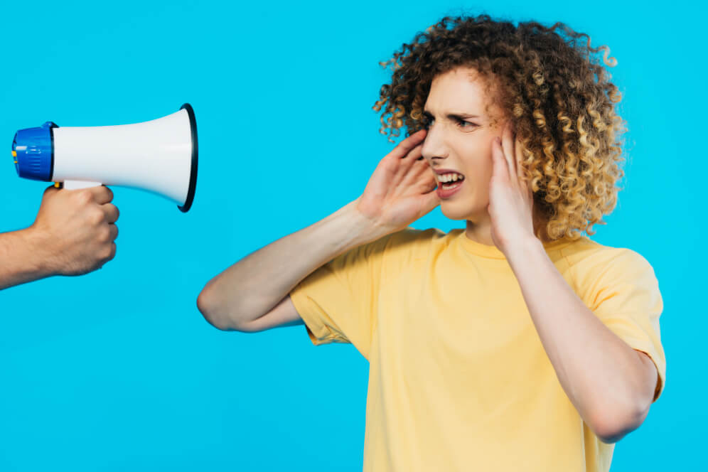 femeie cu mainile la urechi si cu un magnetofon indreptat spre ea