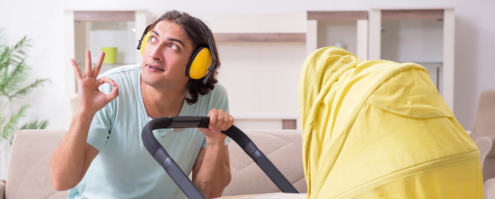 barbat cu casti antifonice pe cap cu semnul ok din mana cu un carut de copil 