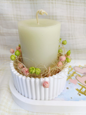 Set decorativ compus dintr-o lumanare cilindrica, alba, din ceara de albine, un vas rotund si o farfurie ovala din ceramica.