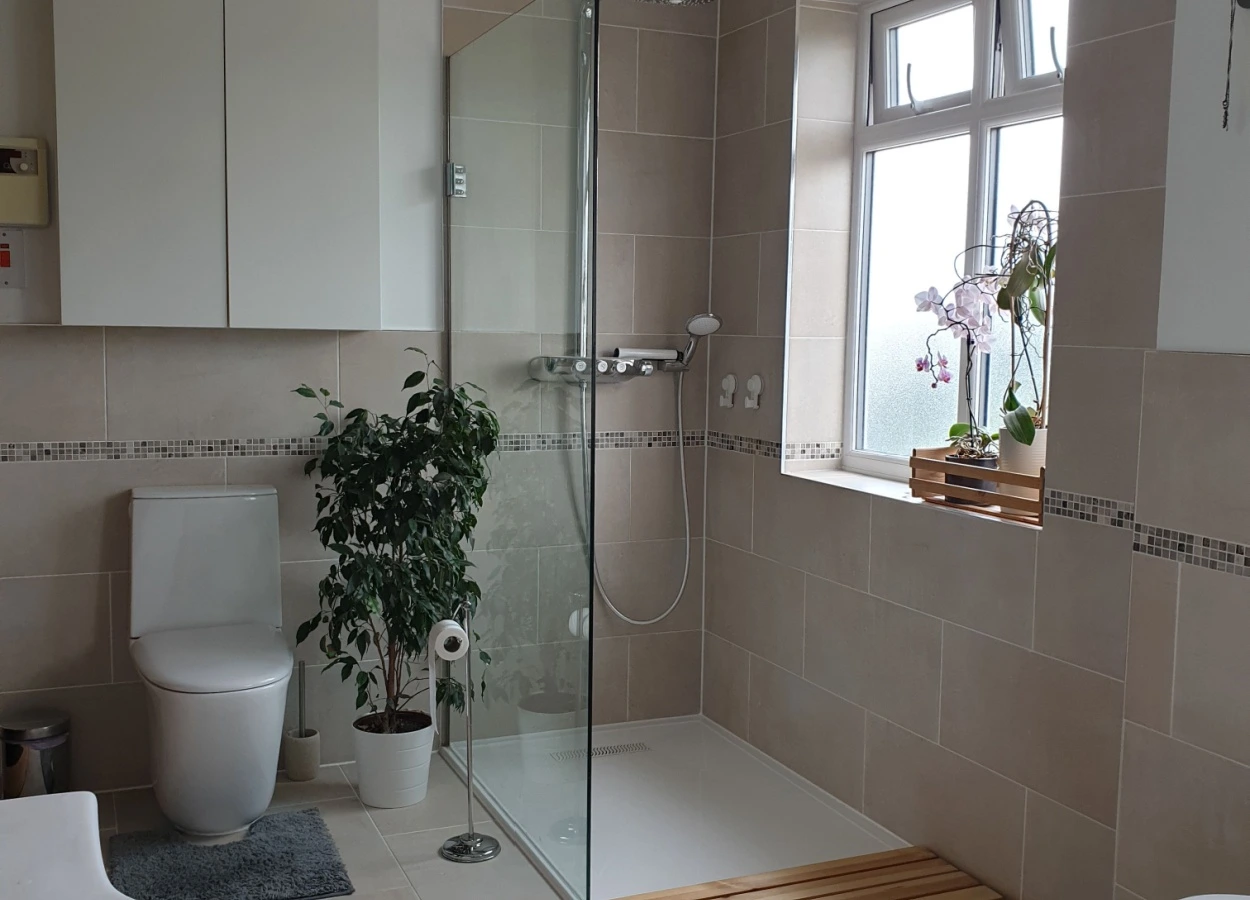 baie cu dus walk-in cu panou de sticla, faianta crem si decor floral