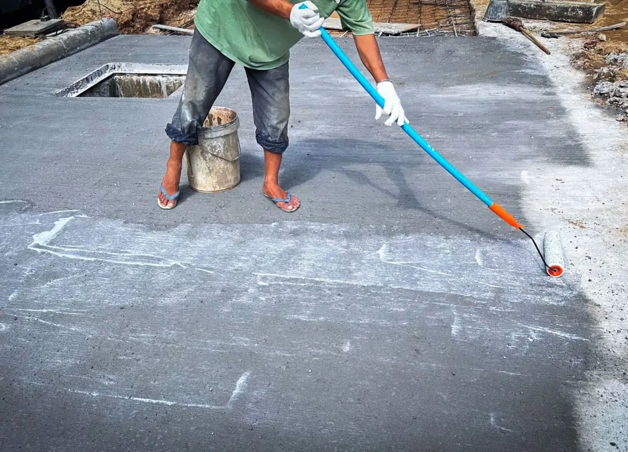 barbat care aplica un primer pentru prevenirea aparitiei crapaturilor in beton