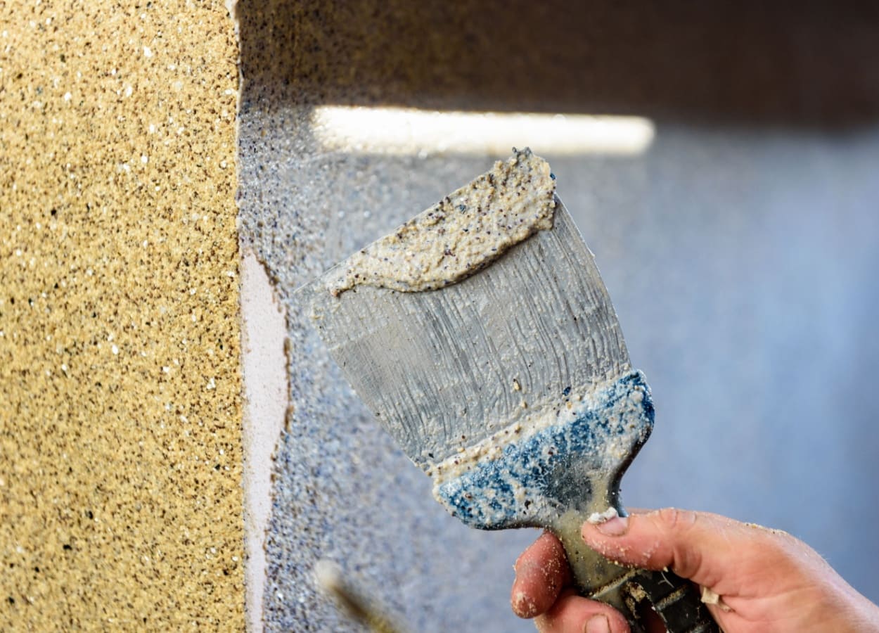 Barbat care aplica tencuiala decorativa