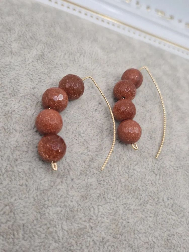 Cercei realizați din sfere de Goldstone (piatra soarelui) și sârmă de cupru placat cu aur 14k. [2]