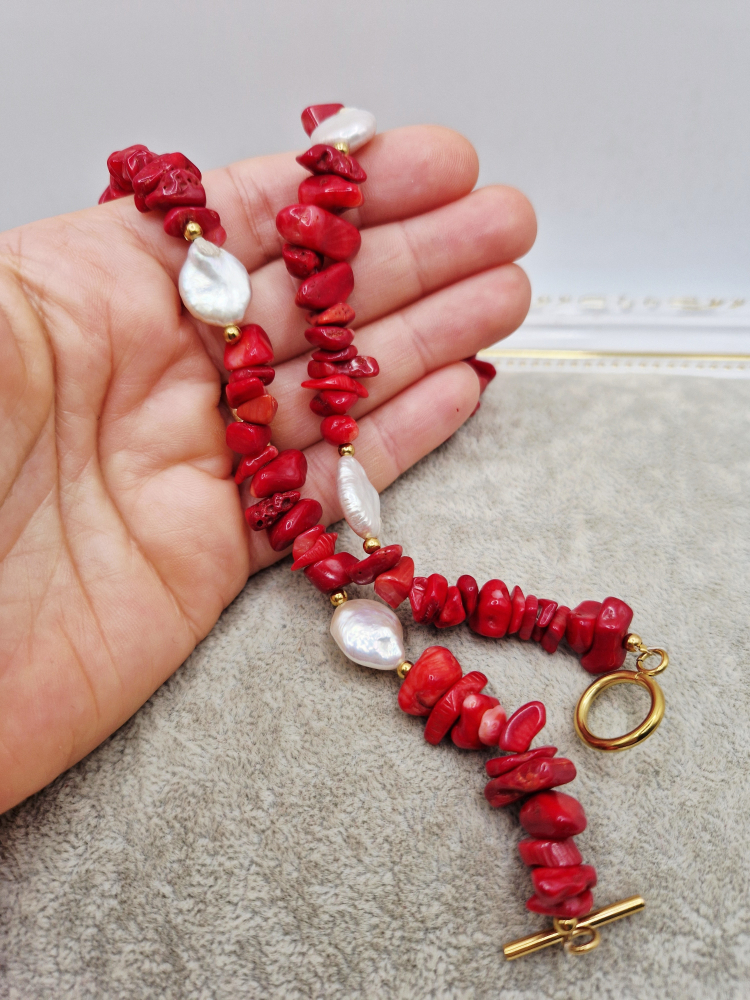 Set alcatuit din Colier si Cercei realizati din Coral rosu chipsuri si Perle naturale banut de categorie AB (mici imperfectiuni). Inchizatoarea si tortitele sunt din otel inoxidabil auriu. Lungime colier 51cm. Perla banut de 13mm. [2]