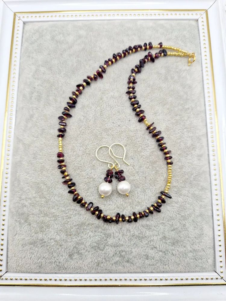 Setul este realizat din granat, forme neregulate și cercei cu perla Mallorca. [3]