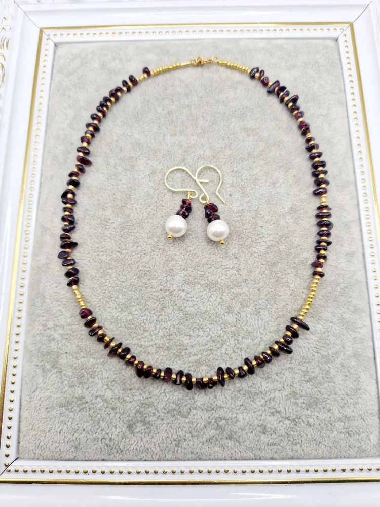 Setul este realizat din granat, forme neregulate și cercei cu perla Mallorca. [2]