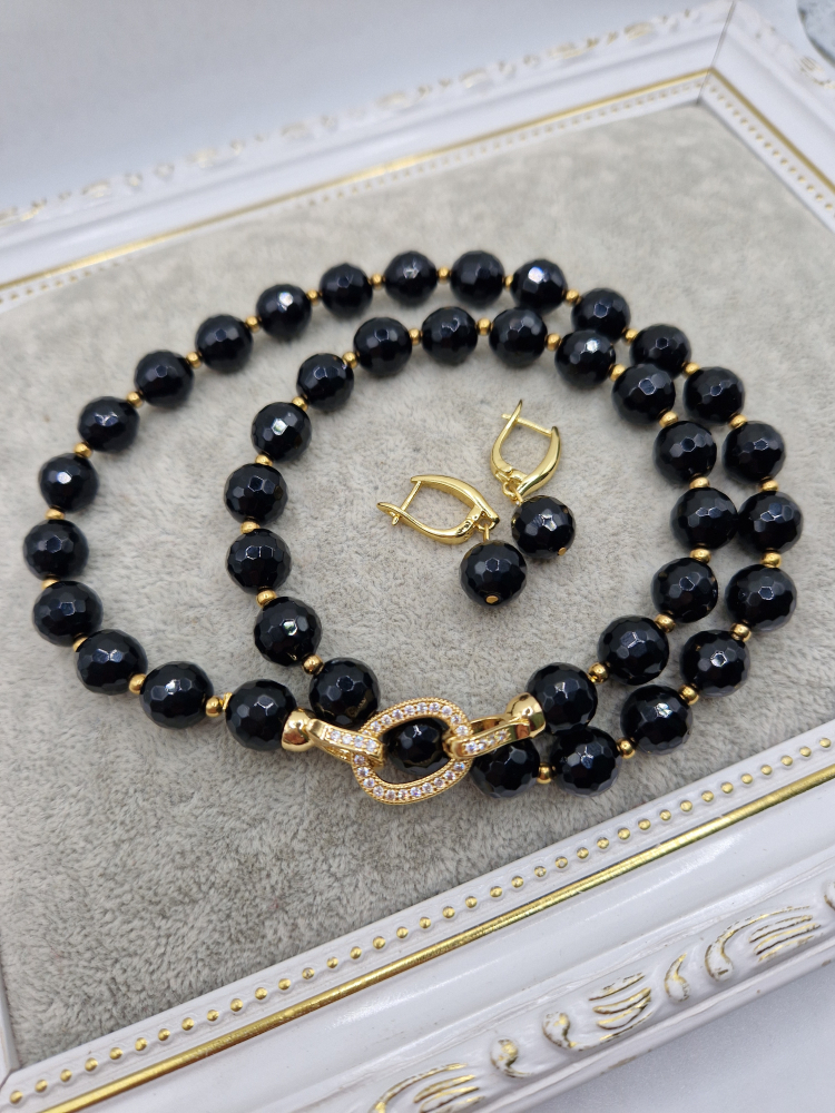 Set alcatuit din colier si cercei realizati din onix negru fatetat si sfere aurii din otel inoxidabil. Inchizatoare si tortite din cubic zirconia. [2]