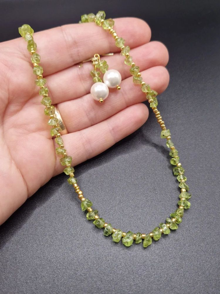 Setul este realizat din peridot, forme neregulate și cercei cu Perlă Mallorca. [3]