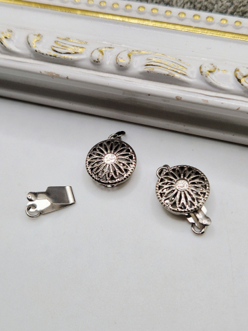 Aliaj argintiu deschis - Inchizatoare din aliaj argintiu cu forma floarea soarelui. ​​​​​​​Se vinde la bucata.