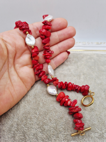 Set alcatuit din Colier si Cercei realizati din Coral rosu chipsuri si Perle naturale banut de categorie AB (mici imperfectiuni). Inchizatoarea si tortitele sunt din otel inoxidabil auriu. Lungime colier 51cm. Perla banut de 13mm. [1]