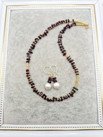 Setul este realizat din granat, forme neregulate și cercei cu perla Mallorca. [2]