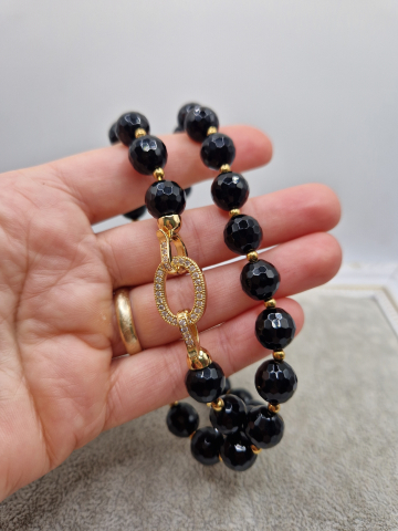 Set alcatuit din colier si cercei realizati din onix negru fatetat si sfere aurii din otel inoxidabil. Inchizatoare si tortite din cubic zirconia. [3]